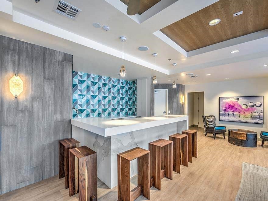 a long bar with wooden stools in a lobby