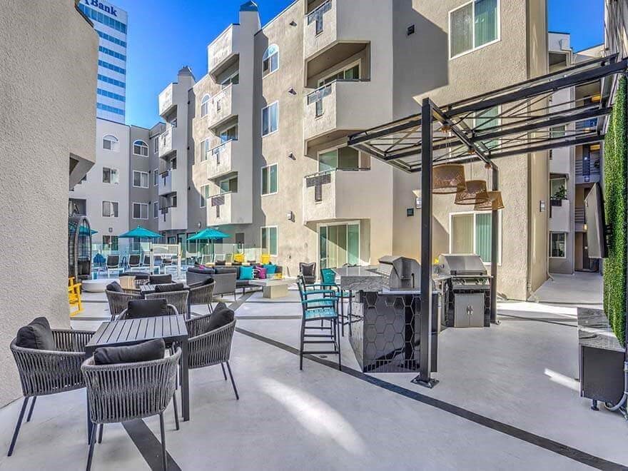 a patio with tables and chairs and a grill