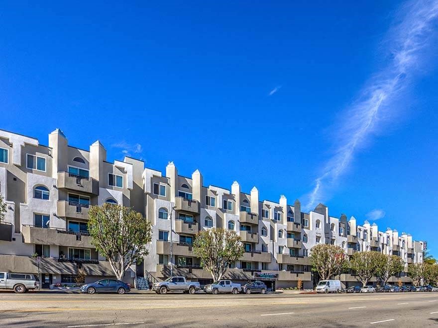 an image of an apartment building with cars parked in front