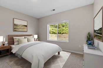 A bedroom with a large bed and a window overlooking a green landscape.