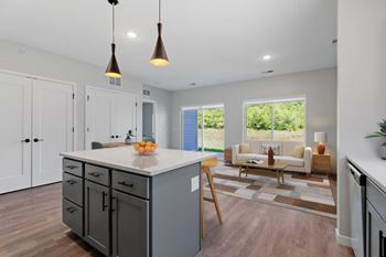A kitchen with a large island and a dining area with a view of the backyard.