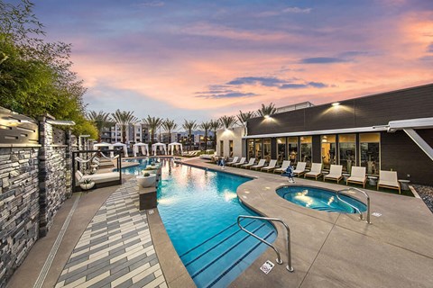 a resort style swimming pool with chaise lounge chairs and a building in the background