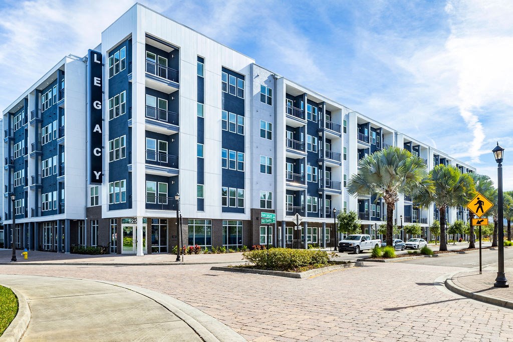 a large blue and white apartment building with palm trees in front of it