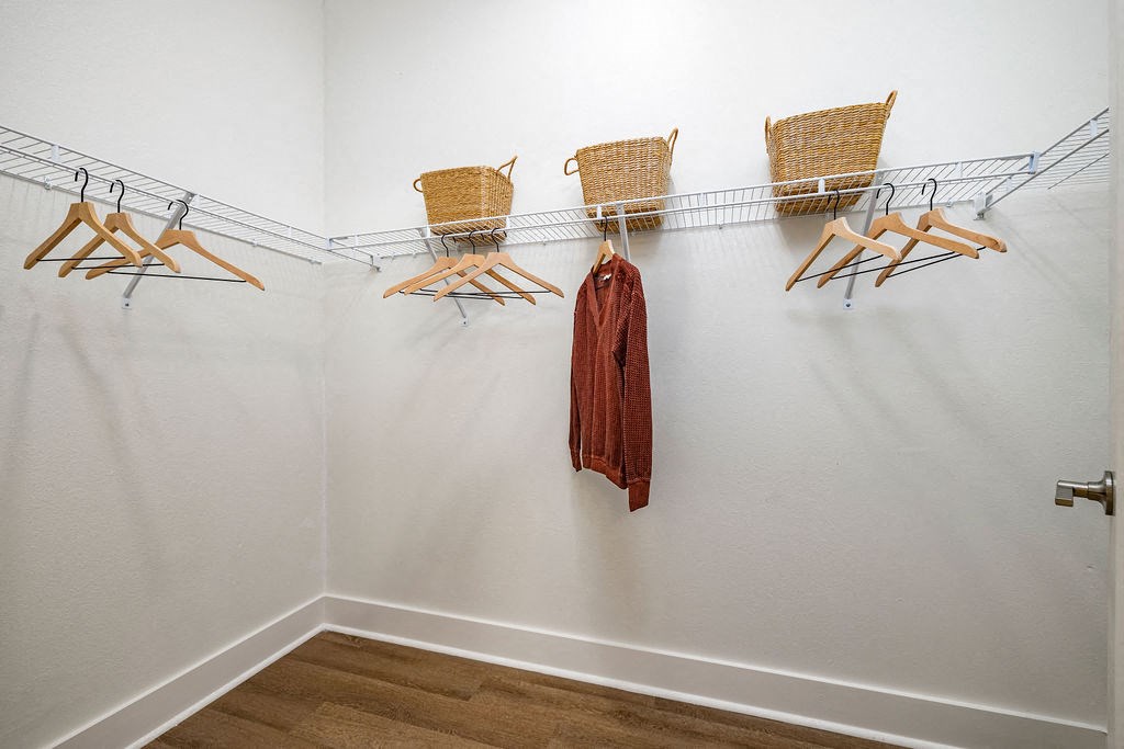 a walk in closet with a metal hanger and three wicker chairs