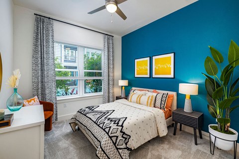 a bedroom with a blue wall and a white ceiling fan