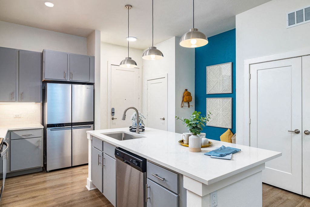 a kitchen with a large white island with a stainless steel refrigerator and dishwasher