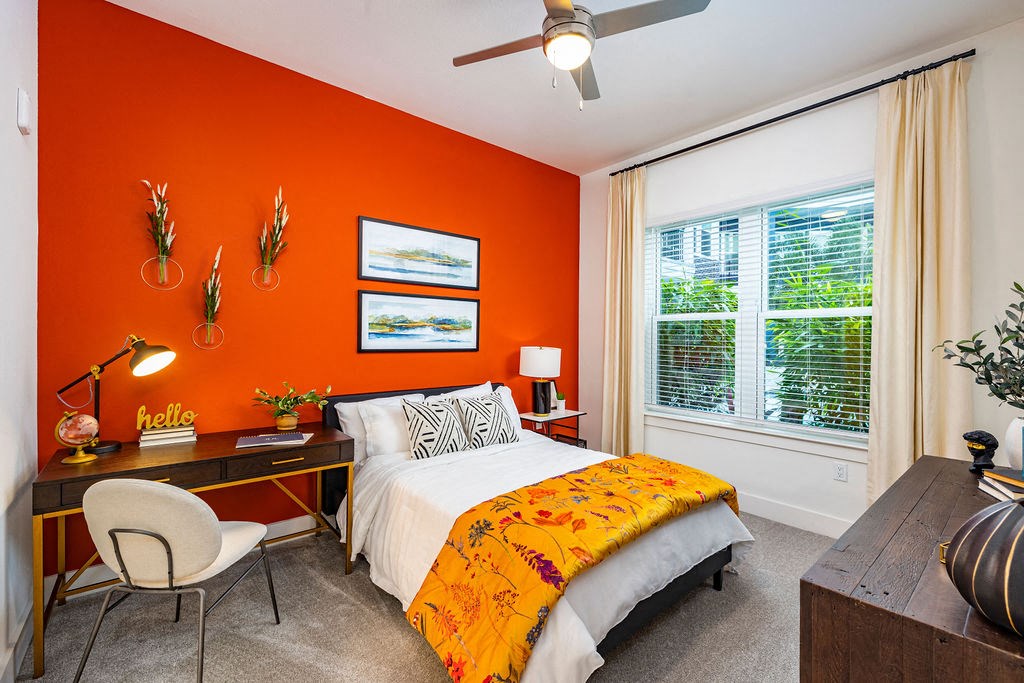 a bedroom with an orange wall and a bed with a yellow and black comforter
