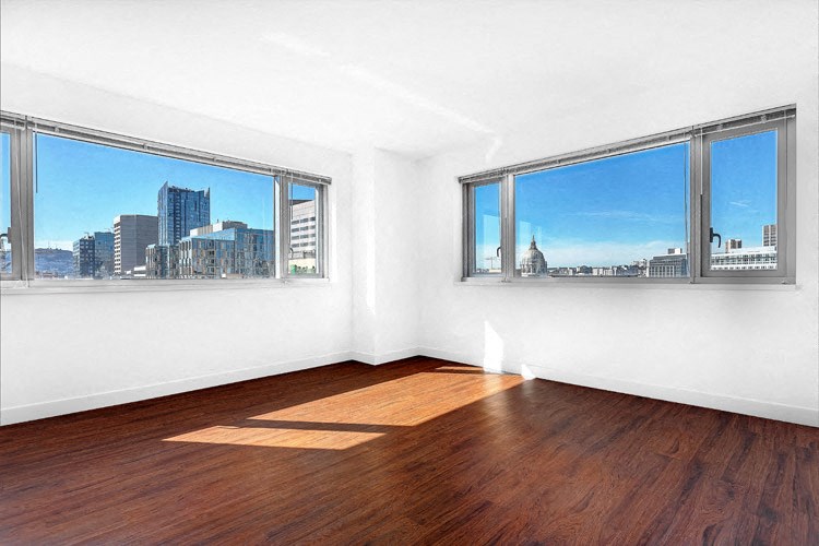 an empty bedroom with three windows and a hardwood floor