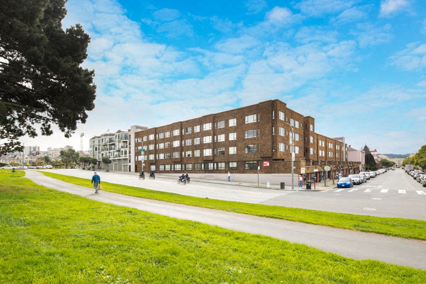 a view of a building on a street with a grassy area in front of it