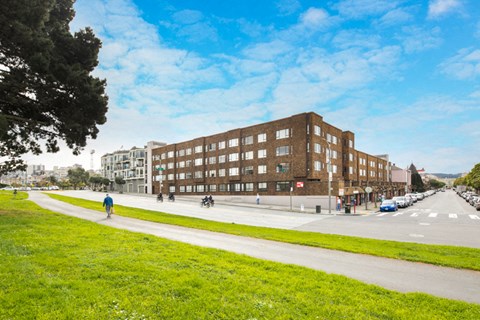 a view of a building on a street with a grassy area in front of it