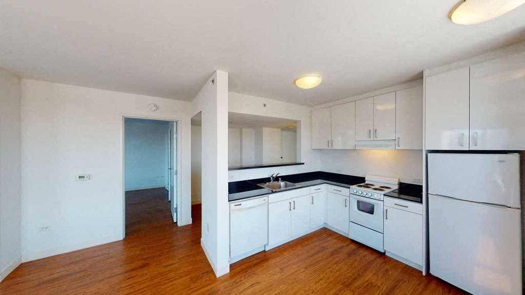 a kitchen with white cabinets and a wooden floor