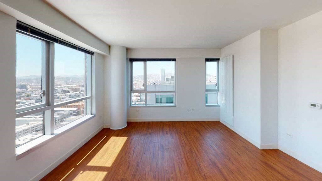 an empty room with hardwood floors and large windows