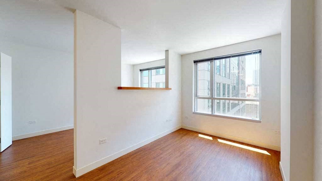 an empty room with a large window and hardwood floors