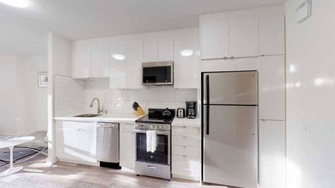 a white kitchen with a stainless steel refrigerator