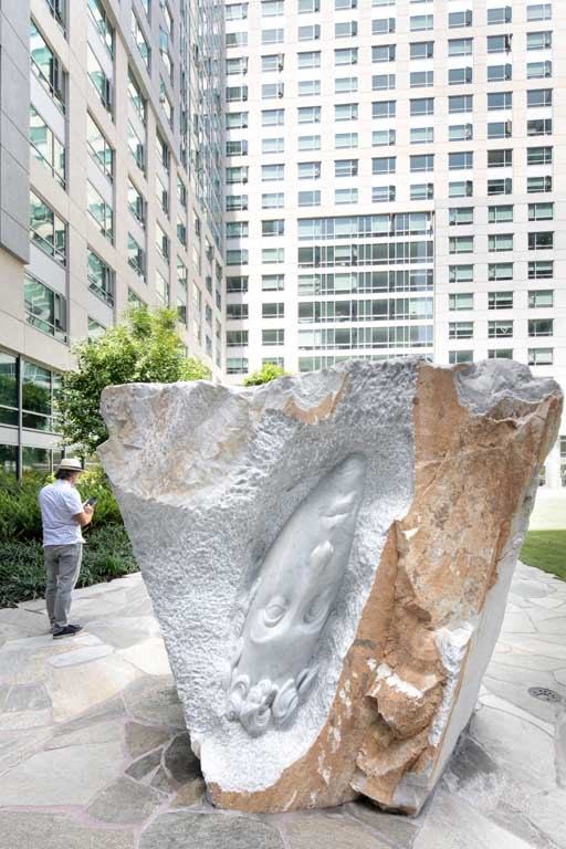 a sculpture of a hand on a rock in front of a building