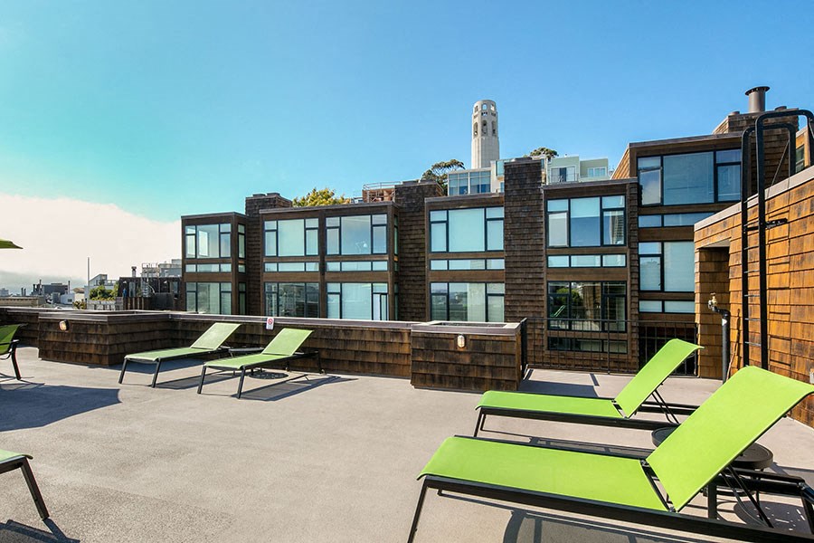 a rooftop deck with lounge chairs and a fire pit