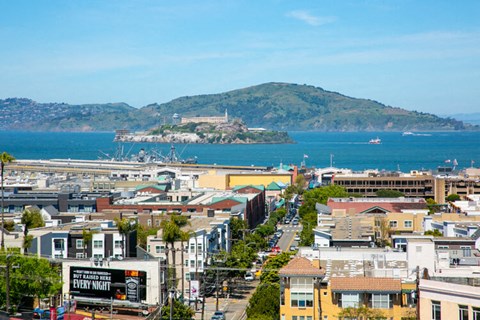a city with a view of the ocean and a mountain in the background
