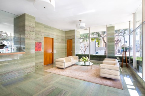 a living room with white furniture and large glass windows