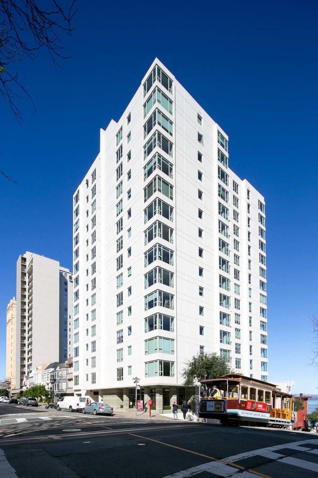 a view from the street of a large white building with a trolley in front of it