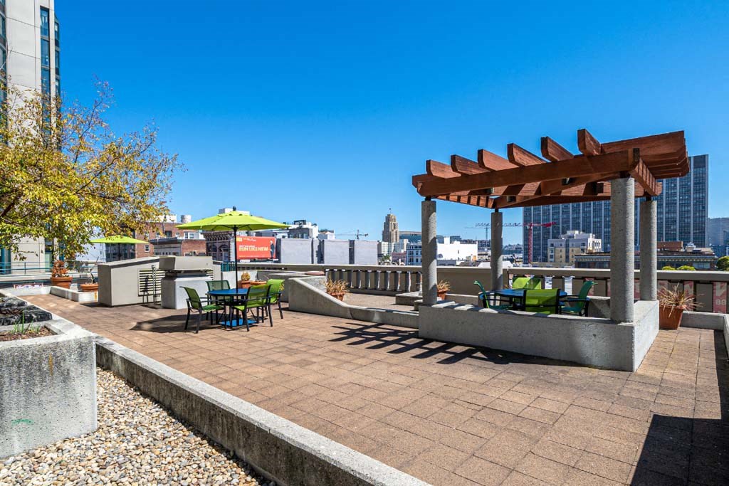 a rooftop patio with a pergola and a view of the city