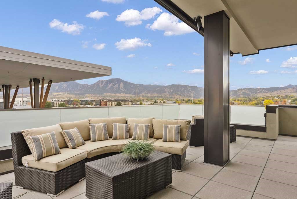 a terrace with couches and a table with a plant on it
