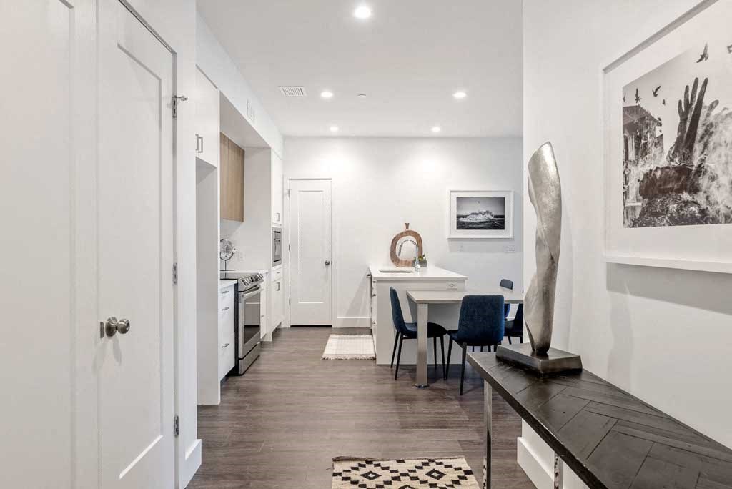 a living area with a table and chairs and a kitchen in the background