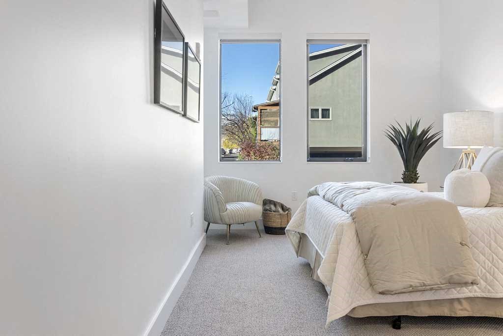 a bedroom with a bed and a chair in front of a window