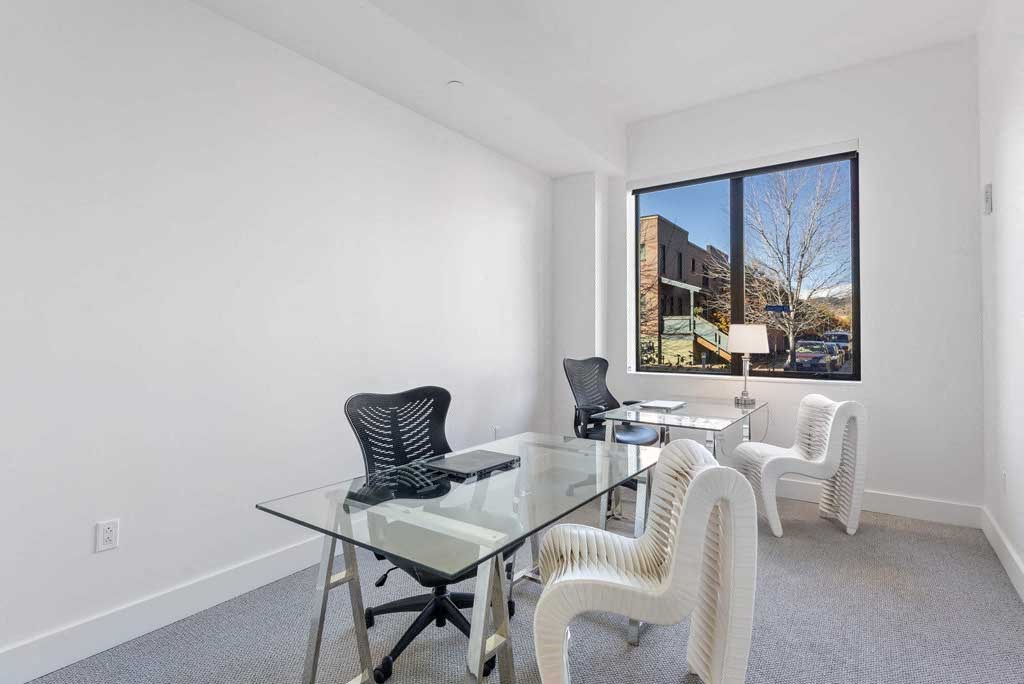 a room with a glass table and chairs and a large window