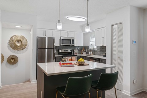 a kitchen with stainless steel appliances and an island with green chairs