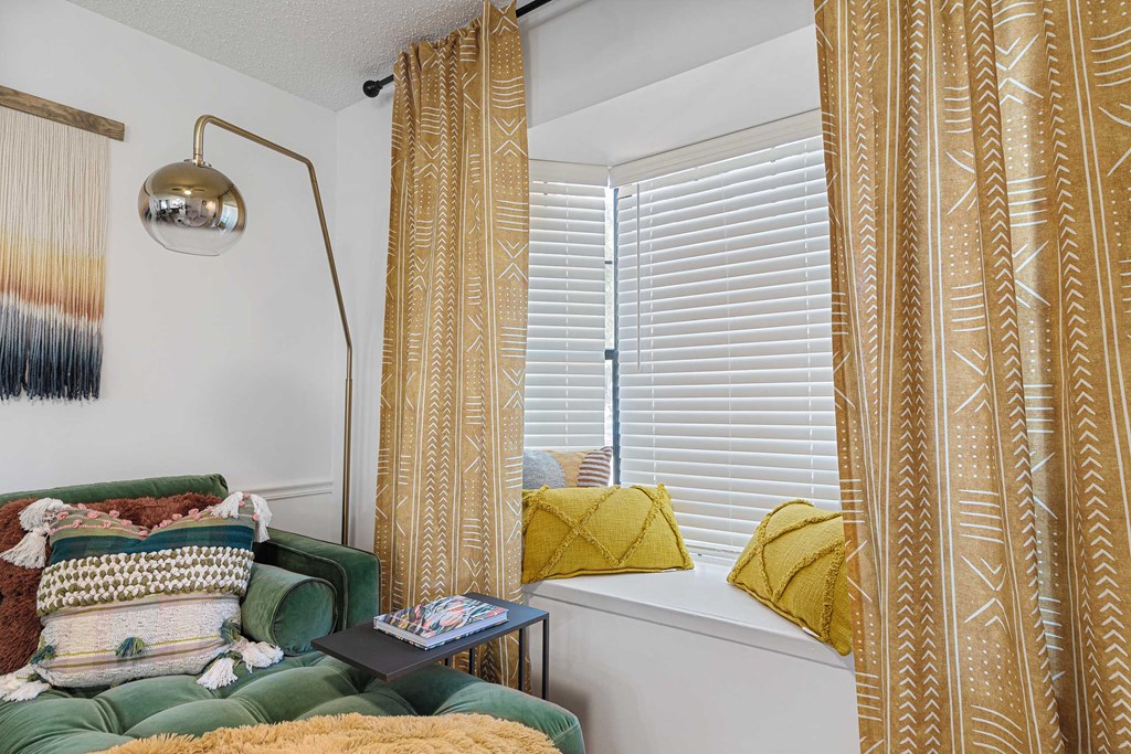 a window seat with yellow curtains and a green sofa