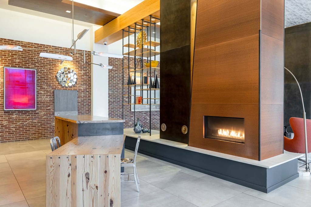 a fireplace in the lobby of a building with a wooden desk and chair