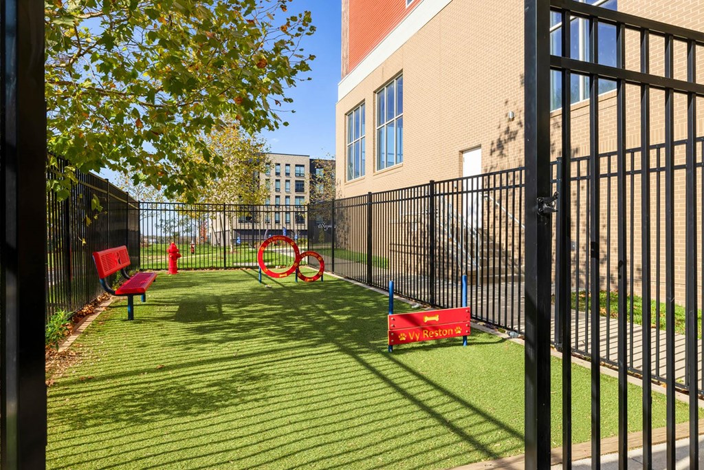 a grassy area with benches and a seesaw in front of a building