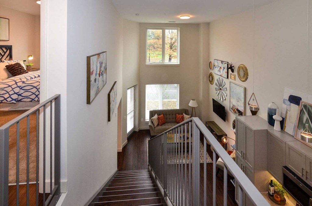 a view from the top of the stairs looking down into the living room and bedroom