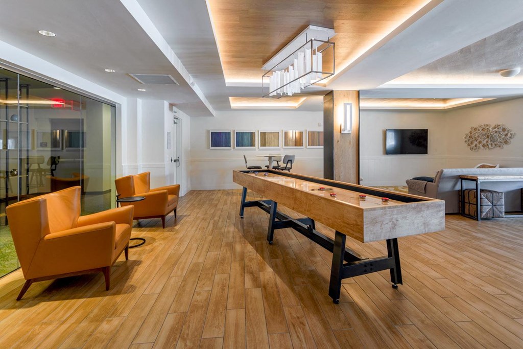 a long shuffleboard table in a large room with hardwood floors and a large window