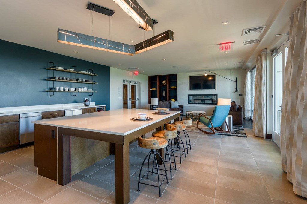 a large table with stools in the center of a room with a couch and a fireplace