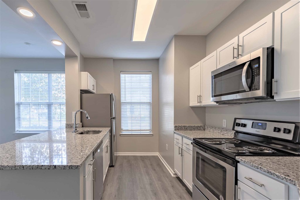 a kitchen with white cabinets and gray countertops