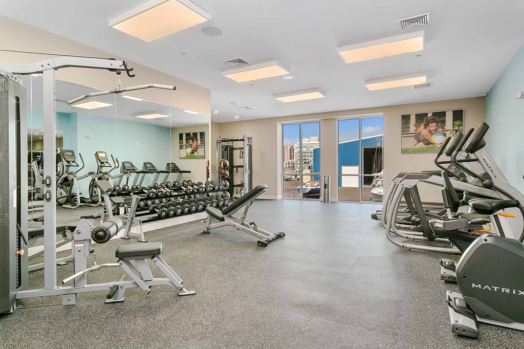 a gym with cardio equipment and a large window