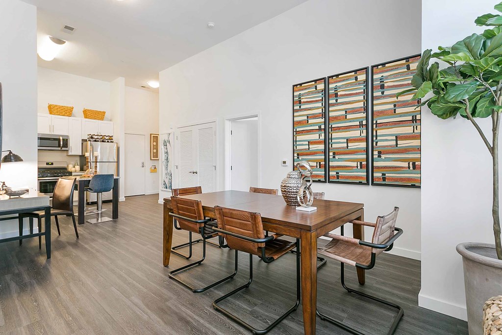 a dining area with a wooden table and chairs and a kitchen in the background
