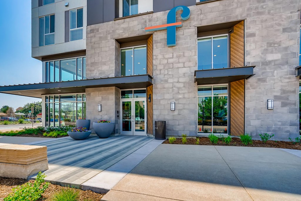 the facade of a building with large glass doors and a sidewalk in front of it