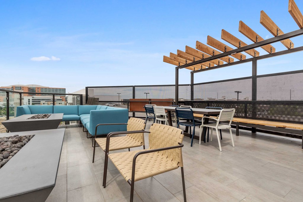 a rooftop patio with tables and chairs and a blue couch