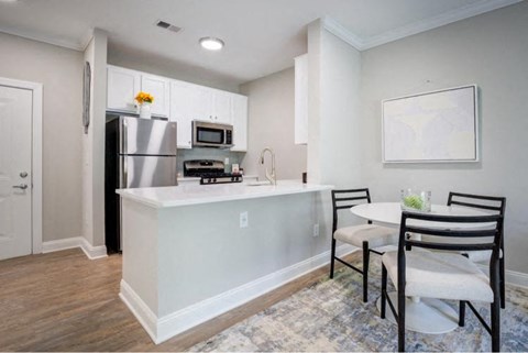 A kitchen with a white island and a dining table with chairs.