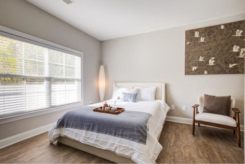 a bedroom with a bed and a chair and a window