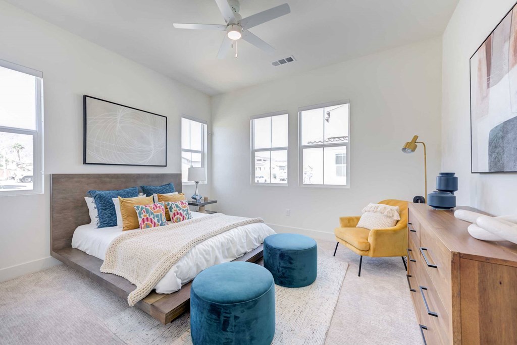 a bedroom with a bed and a desk and a ceiling fan
