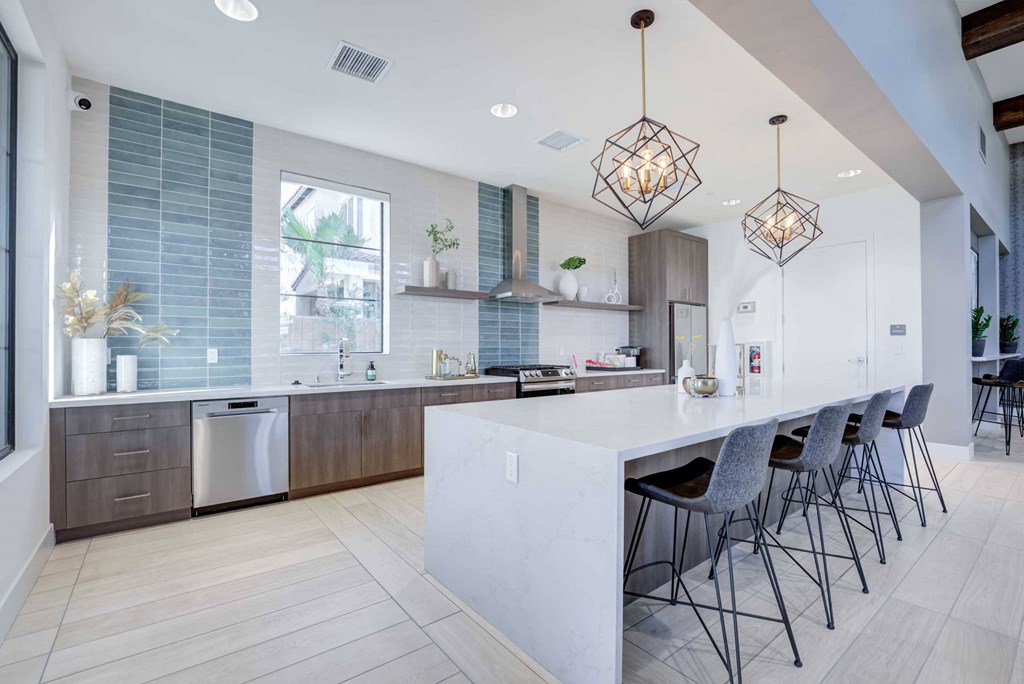 a large white kitchen with a bar and chairs