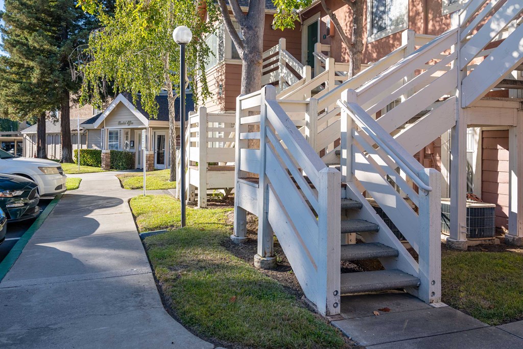 a sidewalk in front of a row of houses with stairs