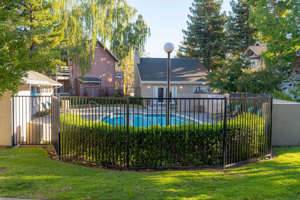 a swimming pool behind a wrought iron fence in a backyard