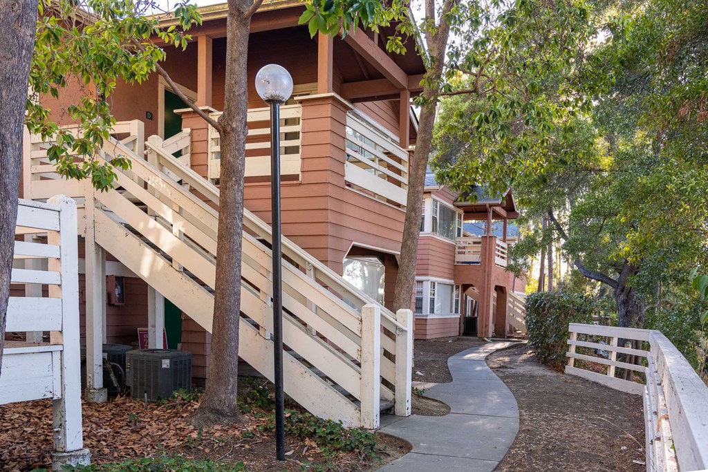a pathway in front of a building with stairs and trees