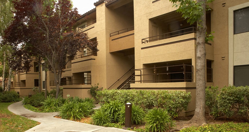 an exterior view of a building with a sidewalk and trees