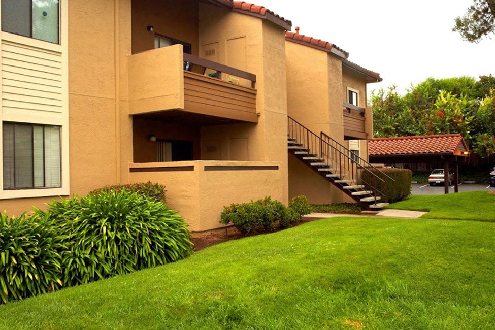 an apartment building with stairs and a green lawn