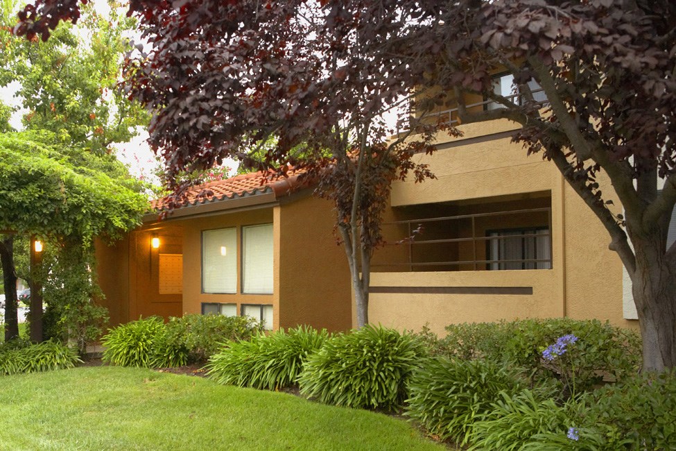 the front of a building with a lawn and trees